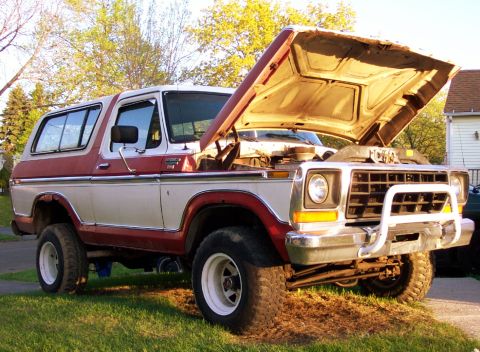 1979 Ford F-250 - This red and white Ford Bronco, likely a 1978 model, is shown with its hood open in a grassy area.