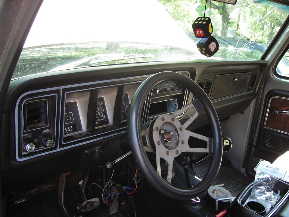 Dashboard and steering wheel of a truck, with fuzzy dice hanging from the rearview mirror
