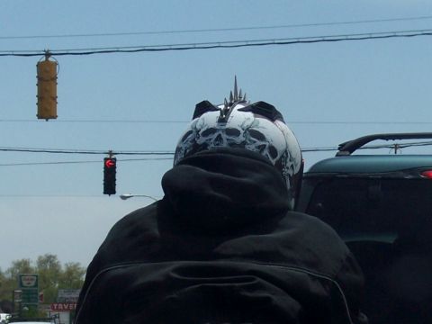 1972 Ford Ranchero - A motorcycle helmet adorned with skull graphics and spikes is visible from behind, alongside a dark SUV in traffic.