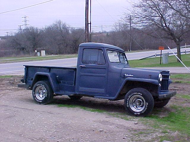 Dark blue vintage Willys pickup truck parked on dirt lot