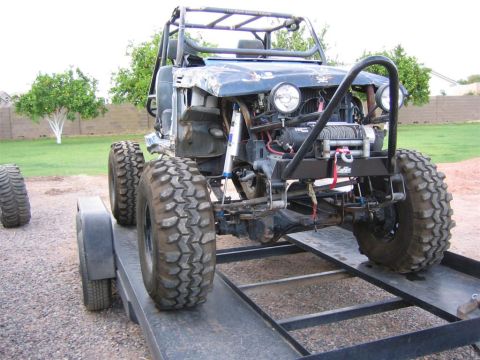 1987 Suzuki Samurai - This heavily modified off-road vehicle is on a trailer, showing its custom roll cage and large tires.