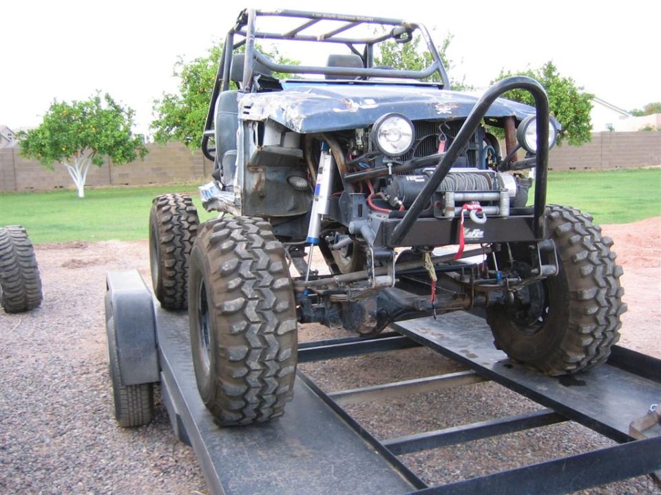 Stripped caged rock crawler on a steel trailer with winch bumper and oversized mud tires