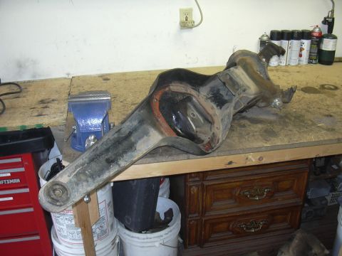 1991 Ford Bronco - Differential axle housing resting on a workbench, with a blue vise visible to the left.