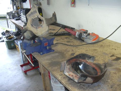 1991 Ford Bronco - Workbench setup with automotive parts, a vise, and a grinder, likely for repair or fabrication.