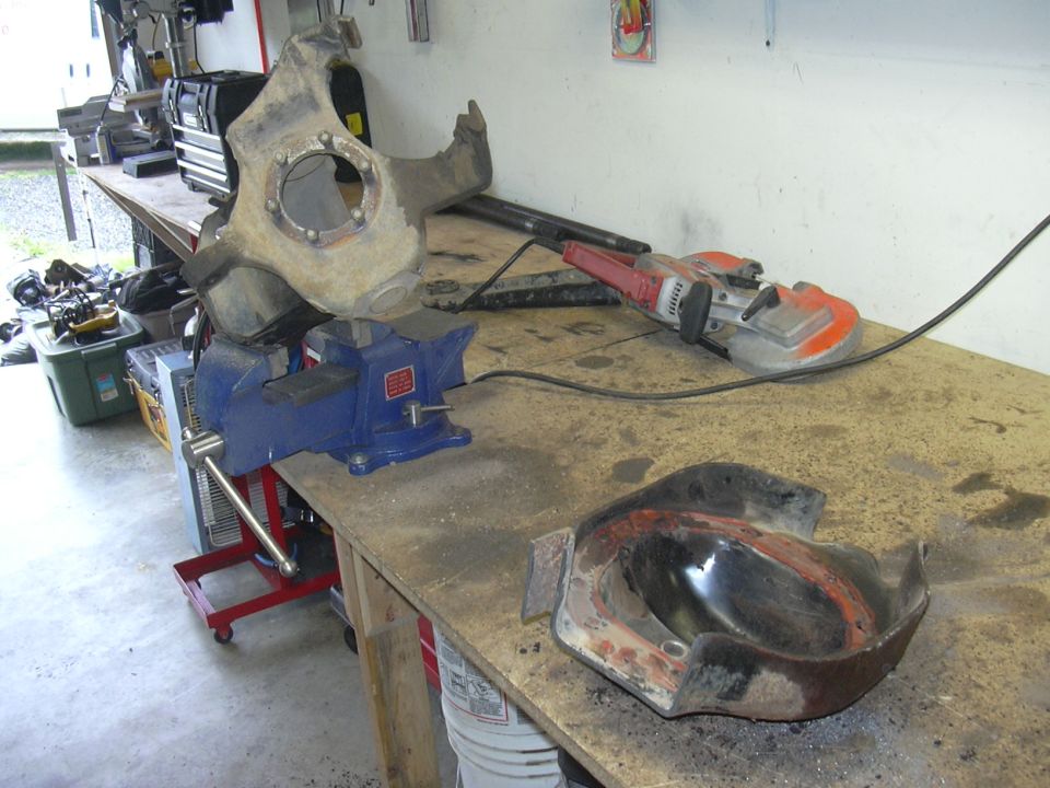 Automotive knuckle and differential cover on workbench with vise and grinder