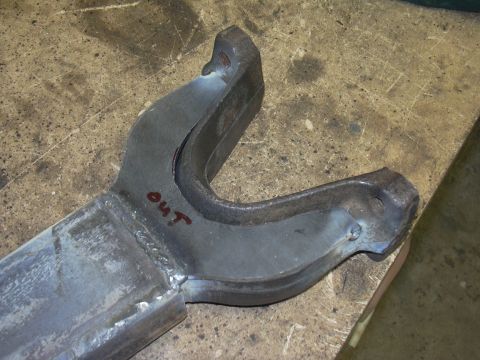 1991 Ford Bronco - Close-up of a metal suspension component marked 'OUT' on a workbench surface.