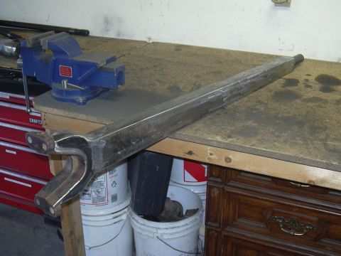 1991 Ford Bronco - A metal suspension part is secured on a workbench with a vise and buckets nearby.