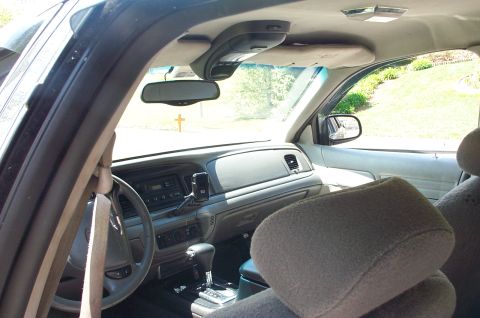 1999 Ford Crown Victoria - Interior view of a Ford Crown Victoria shot from the passenger side, showing the gray dashboard, steering wheel, column-mounted shifter, ce…