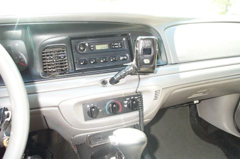 1999 Ford Crown Victoria - Interior dashboard view of a gray Ford Crown Victoria showing the center stack with an AM/FM radio displaying a clock, rotary climate contr…