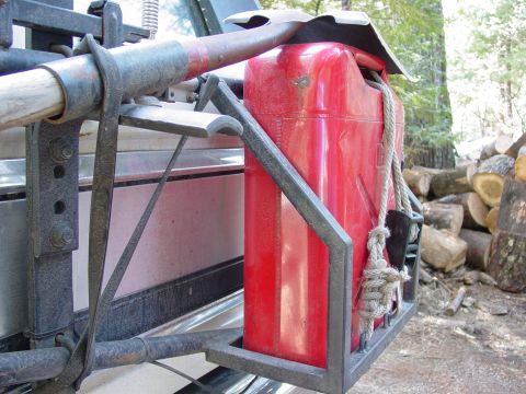 1986 Ford Bronco - A red jerry can and shovel are attached to the back of a vehicle, with firewood visible in the background.