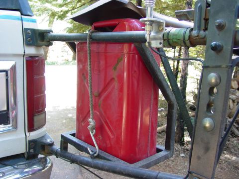 1986 Ford Bronco - Jerry can mounted on a trailer hitch carrier, with part of a white vehicle visible on the left.