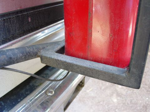 1986 Ford Bronco - A red jerry can is secured in a metal bracket on the rear of a vehicle.