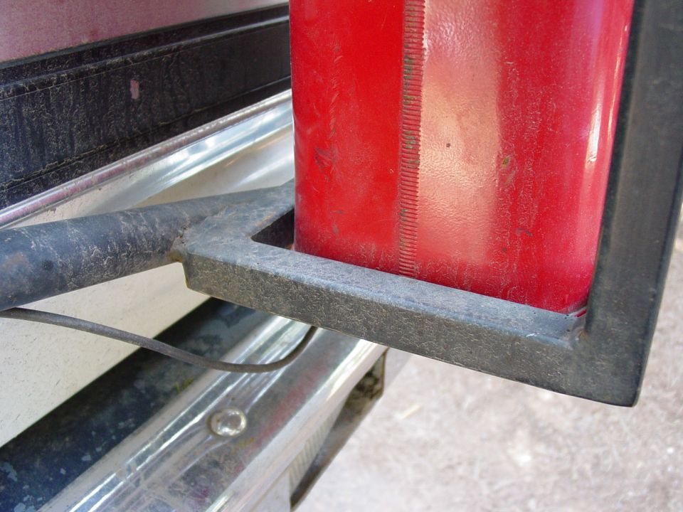 Red jerry can in a metal holder on a vehicle's rear bumper