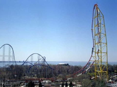 1968 Ford Mustang - A towering roller coaster dominates the skyline, with another amusement ride visible in the distance.