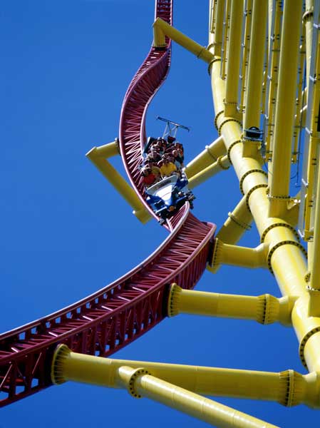 1968 Ford Mustang - A roller coaster train navigates a twisty section of track under a clear blue sky.