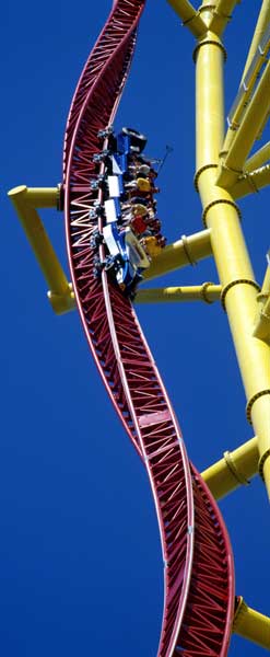 1968 Ford Mustang - A roller coaster train navigates a steep section of track against a clear blue sky.