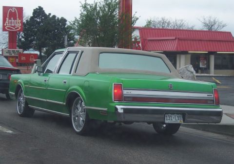 1972 Ford Ranchero - A green Lincoln Town Car is seen from the rear, parked near an Arby's restaurant.