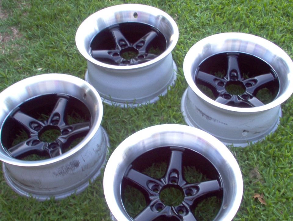 Four aftermarket five-spoke wheels with polished lips and black centers on grass