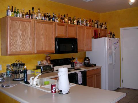1984 Ford Bronco - A kitchen scene with various appliances and a large collection of bottles displayed on top of the cabinets.