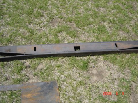 1990 Ford Bronco - A metal fabrication part with square cutouts lies on the grass, possibly for a vehicle.