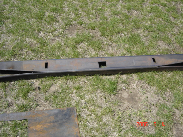 Metal fabrication part with square cutouts on grassy ground