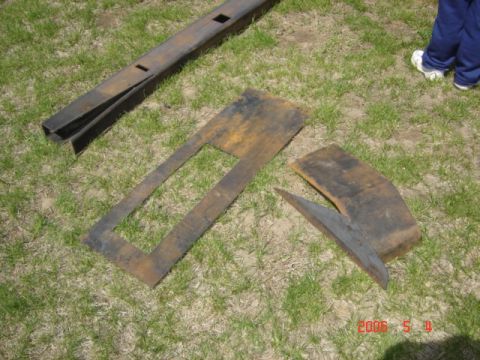 1990 Ford Bronco - Several rusted metal parts are scattered on the grass, with a person's legs visible in the background.
