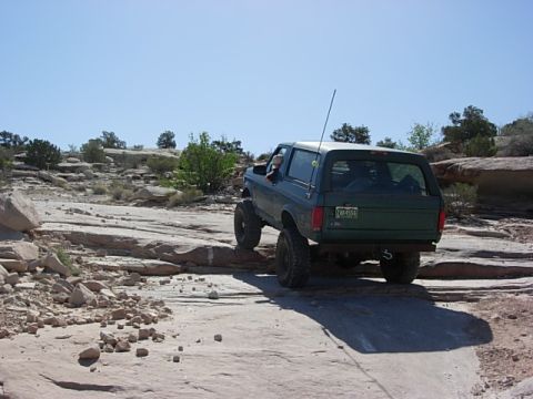 1987 Ford Bronco - A green 1987 Ford Bronco navigates a rocky trail, its off-road capabilities.