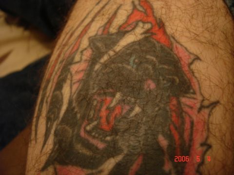 1990 Ford Bronco - A close-up view of a tattoo a black panther with red flames on a person's leg.