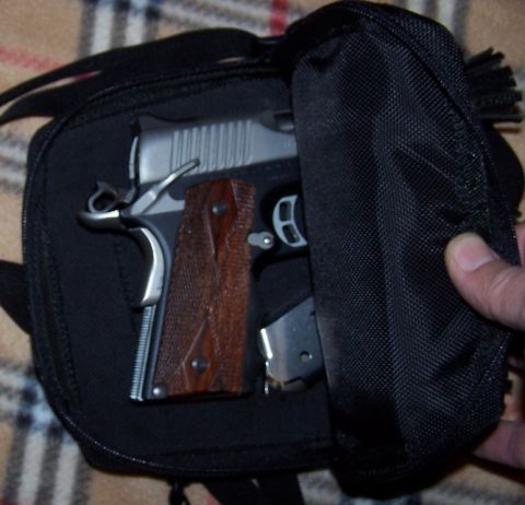 1990 Ford Bronco - A hand opens a black bag revealing a pistol with wooden grips and a magazine inside.