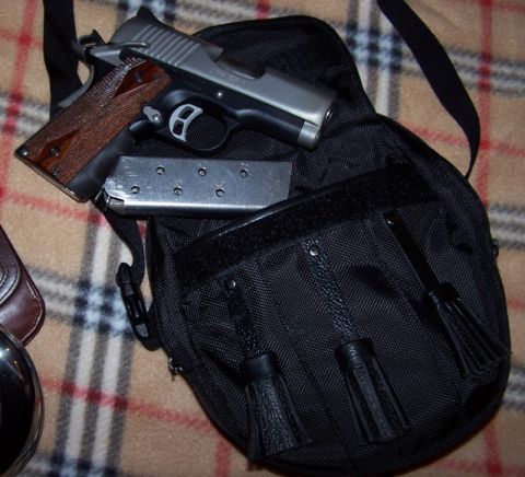 1990 Ford Bronco - A pistol and its magazine are placed inside a black bag with decorative tassels.