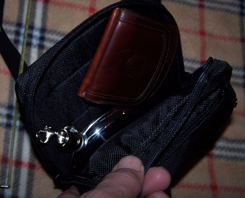 Black fabric bag with brown leather wallet and shiny metal object inside