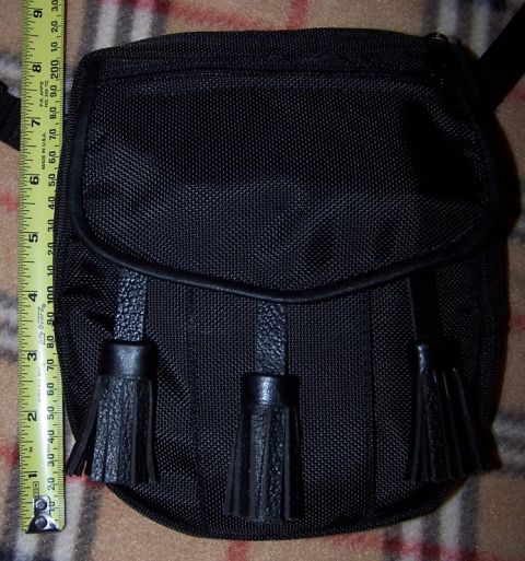 1990 Ford Bronco - A black sporran with decorative tassels is shown next to a measuring tape, indicating its size.