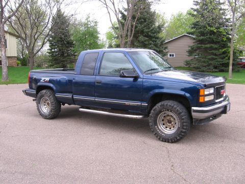 1995 GMC Sierra 1500 - This blue 1995 GMC Sierra 1500 pickup truck is viewed from a three-quarter front angle on a paved surface.