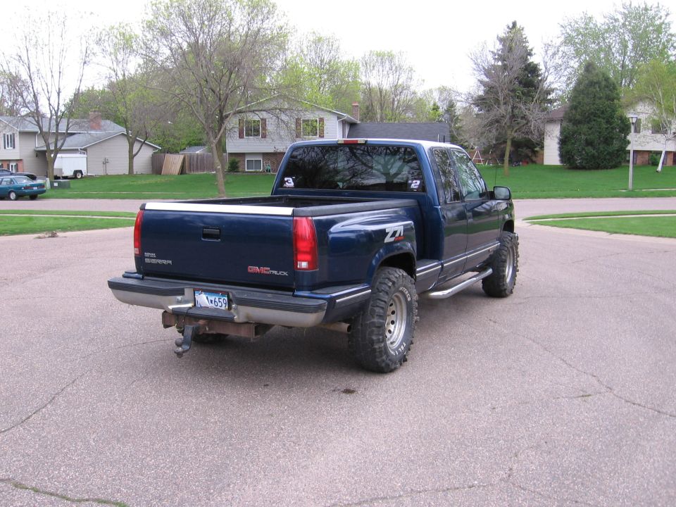 Rear 3/4 view of dark blue GMC Sierra pickup with Z71 badge parked on a residential street