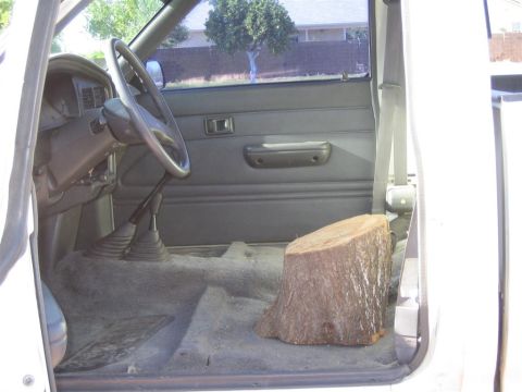 1994 Ford Bronco - A tree stump is placed on the passenger floor inside the cab of a pickup truck.