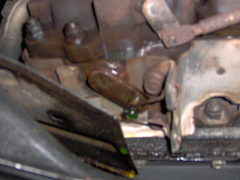 Blurry underbody shot of rusty engine components with green coolant drips visible