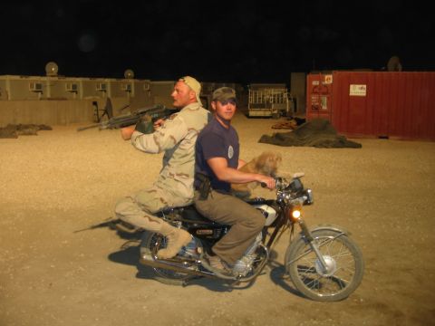 1979 Ford Bronco - Two men and a dog ride a motorcycle at night in a desert-like environment with buildings in the background.