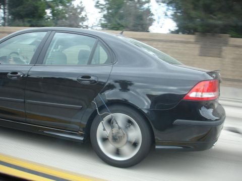 1993 Ford Taurus - A black sedan is captured from the side, showing a device attached to its rear wheel, likely for testing purposes.