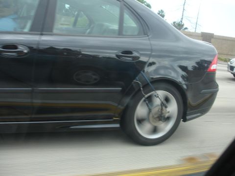 1993 Ford Taurus - Side view of a black sedan showing a blue strap attached to the rear wheel assembly.
