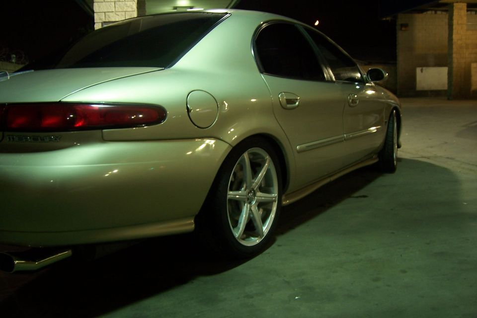 Rear view of gold 1998 Mercury Sable with aftermarket wheels