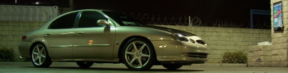 Gold sedan with aftermarket wheels parked at night