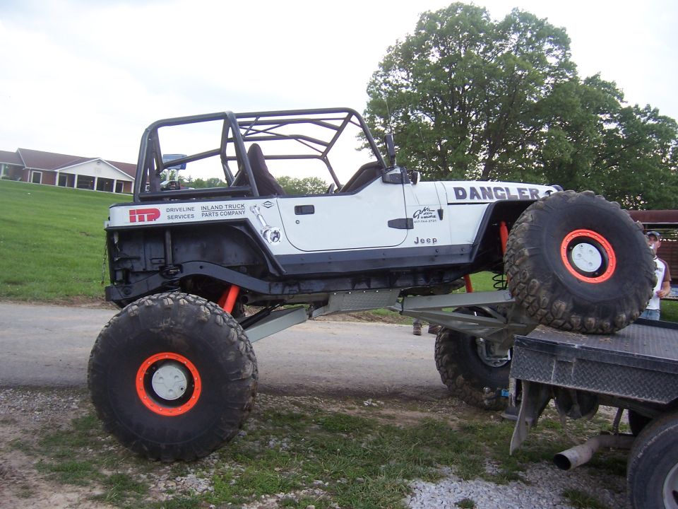 White lifted Jeep Wrangler with roll cage on huge mud tires and orange beadlocks