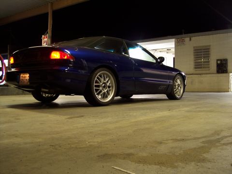 1995 Ford Probe - A blue 1995 Ford Probe GT is shown from the rear 3/4 angle, highlighting its aftermarket rims.
