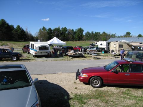 1991 Ford LTD Crown Victoria - A red sedan with a light bar is parked in a lot with several other vehicles and RVs under a clear sky.
