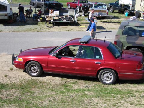 1991 Ford LTD Crown Victoria - Side view of a red 1991 Ford Crown Victoria LTD sedan, equipped with a light bar, parked outdoors.