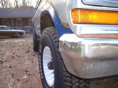 1978 Ford Bronco - This Bronco's front end is shown with a chrome bumper and amber turn signal. A second vehicle is visible in the background.