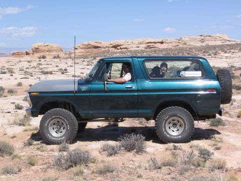 1979 Ford Bronco - Side view of a 1979 Ford Bronco with two occupants, parked in a rocky, arid landscape.