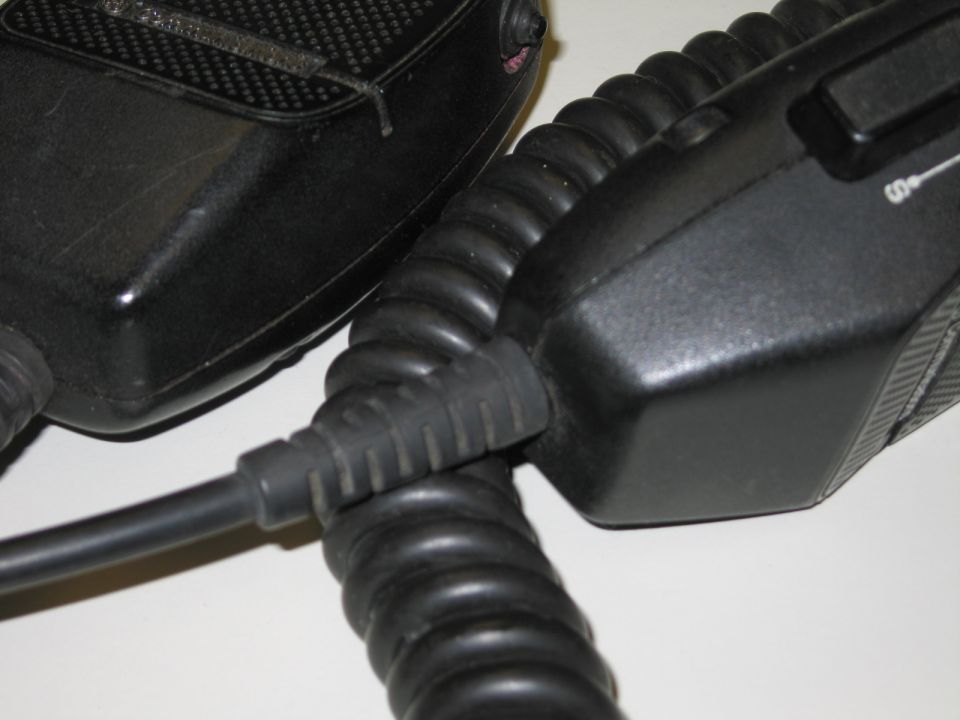Close-up of two black handheld microphones with coiled cords joined at a cable