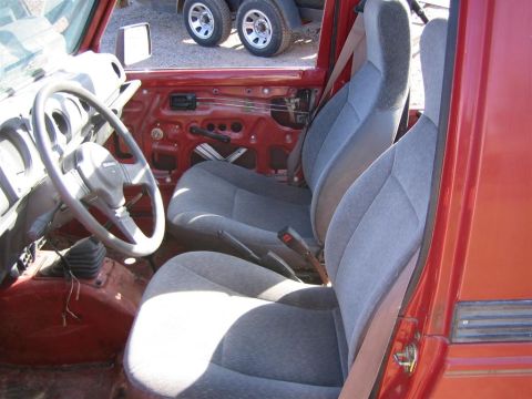1987 Suzuki Samurai - The interior of a Suzuki Samurai shows its seats and steering wheel with the door panel removed.