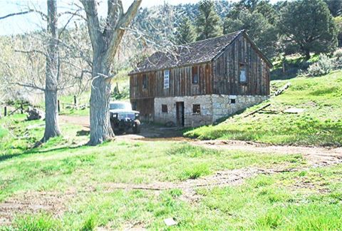 1986 Ford Bronco - A dark SUV is parked in front of an old wooden barn on a grassy hill.